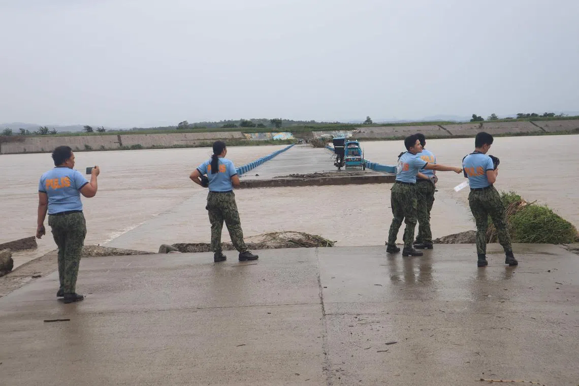 Police personnels monitor a flooded bridge after the river overflowed due to heavy rains brought about by Typhoon Doksuri in Ilagan town, Isabela province on July 26, 2023. (Photo by STRINGER / AFP)