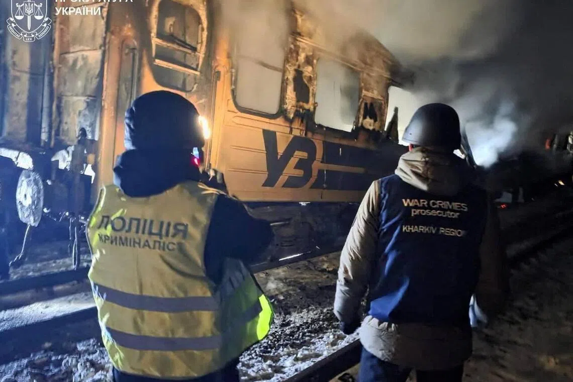 A war crimes prosecutor and a police officer working at the scene of a Russian drone attack on a passenger train in Ukraine's Kharkiv region on Jan 27.