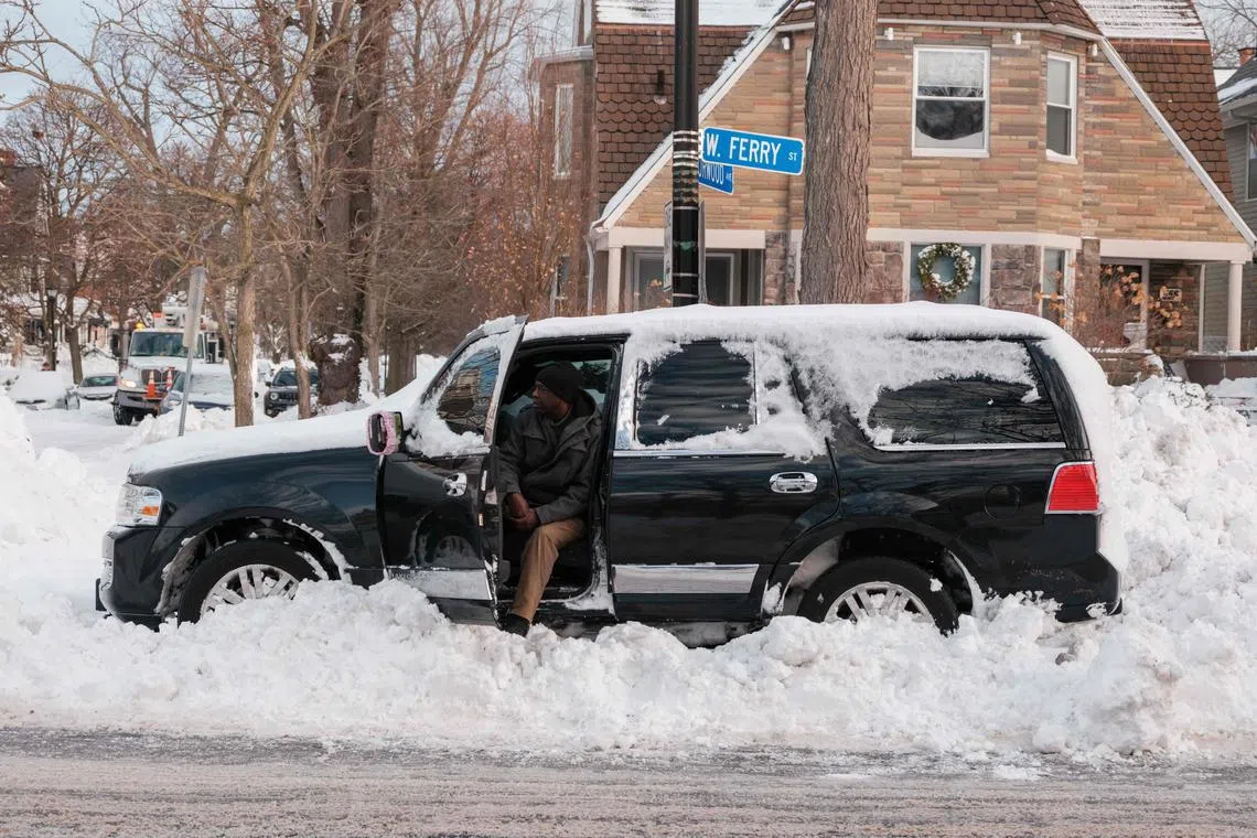 A resident who abandoned his car after getting stuck on Christmas Eve waits for help starting it in Buffalo, New York, on Dec 28, 2022.