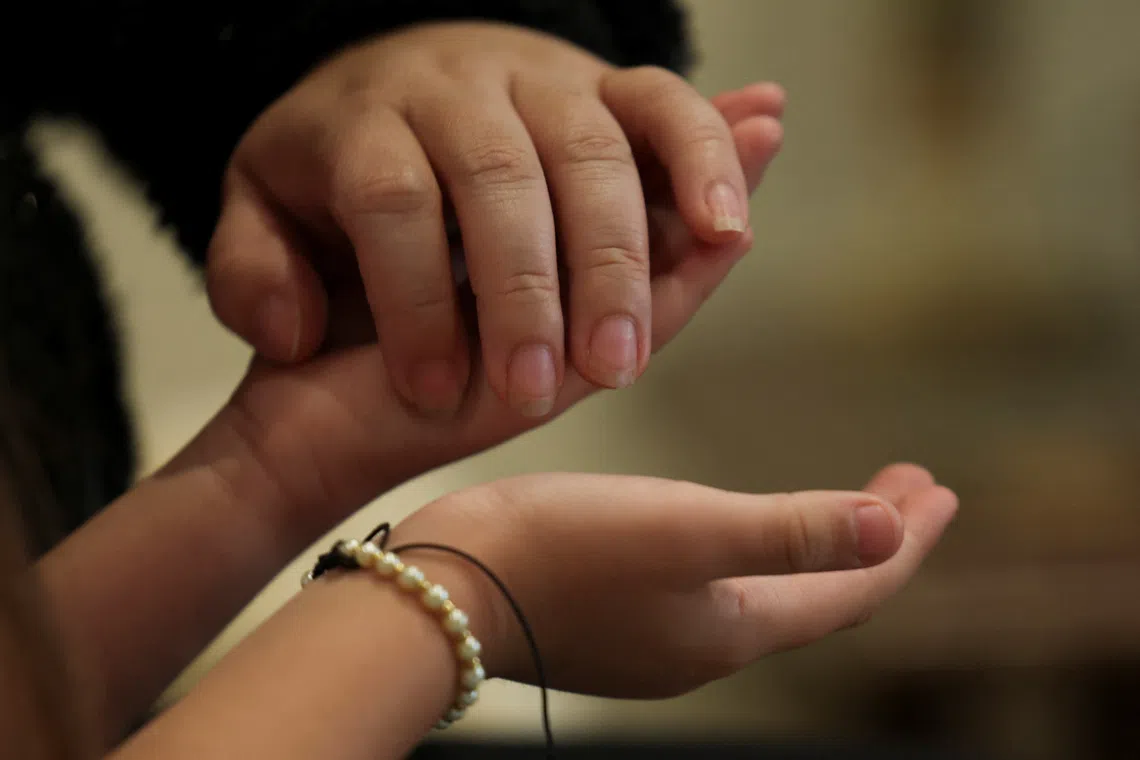Kelly Johana Vargas Lozano, 30, holds the hands of her daughter Maria Paula Herrera Vargas, 6, at the place where they are staying after being deported from the United States, amid the immigration crackdown by the U.S. government, in Bogota, Colombia, November 19, 2025. REUTERS/Luisa Gonzalez