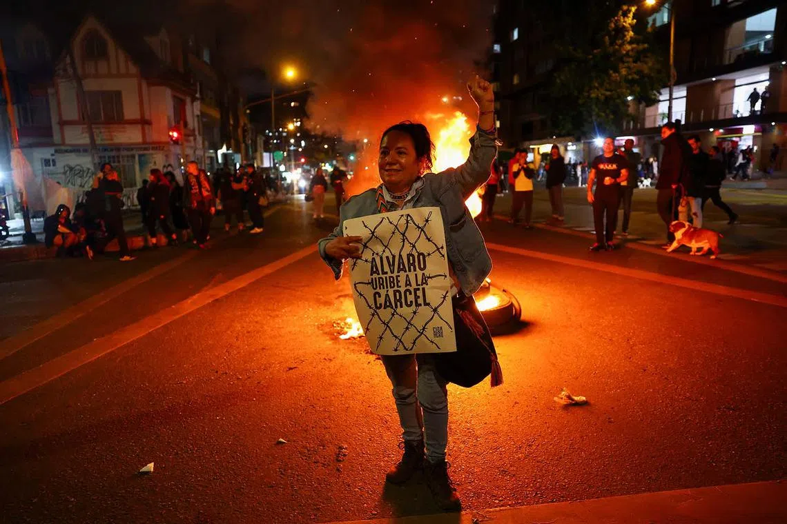 A woman holding a poster that reads "Alvaro Uribe goes to prison", as people gather in celebration after a judge found former Colombian President Alvaro Uribe guilty of abuse of process and bribery of a public official, in Bogota, Colombia July 28, 2025. 