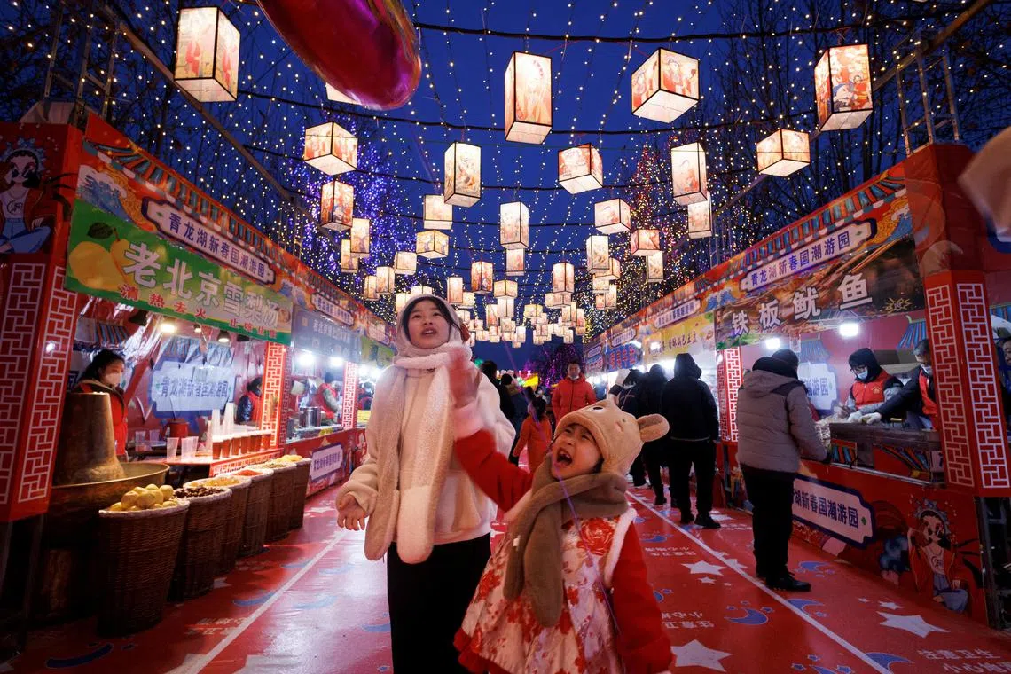 People walk through a part of a Spring Festival light installation in Qinglonghu Park in Beijing.