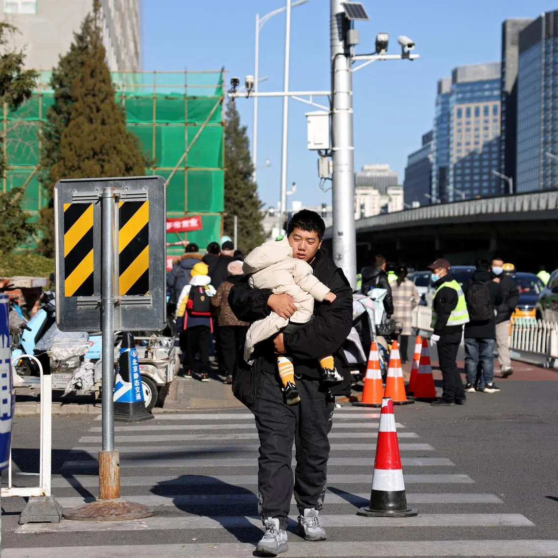 A man carries a child outside a children's hospital in Beijing, China November 24, 2023. REUTERS/Florence Lo