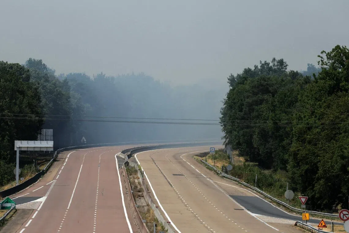 The A6 highway is closed to traffic as a plume of smoke rises into the sky from a forest fire in the Fontainebleau Forest.