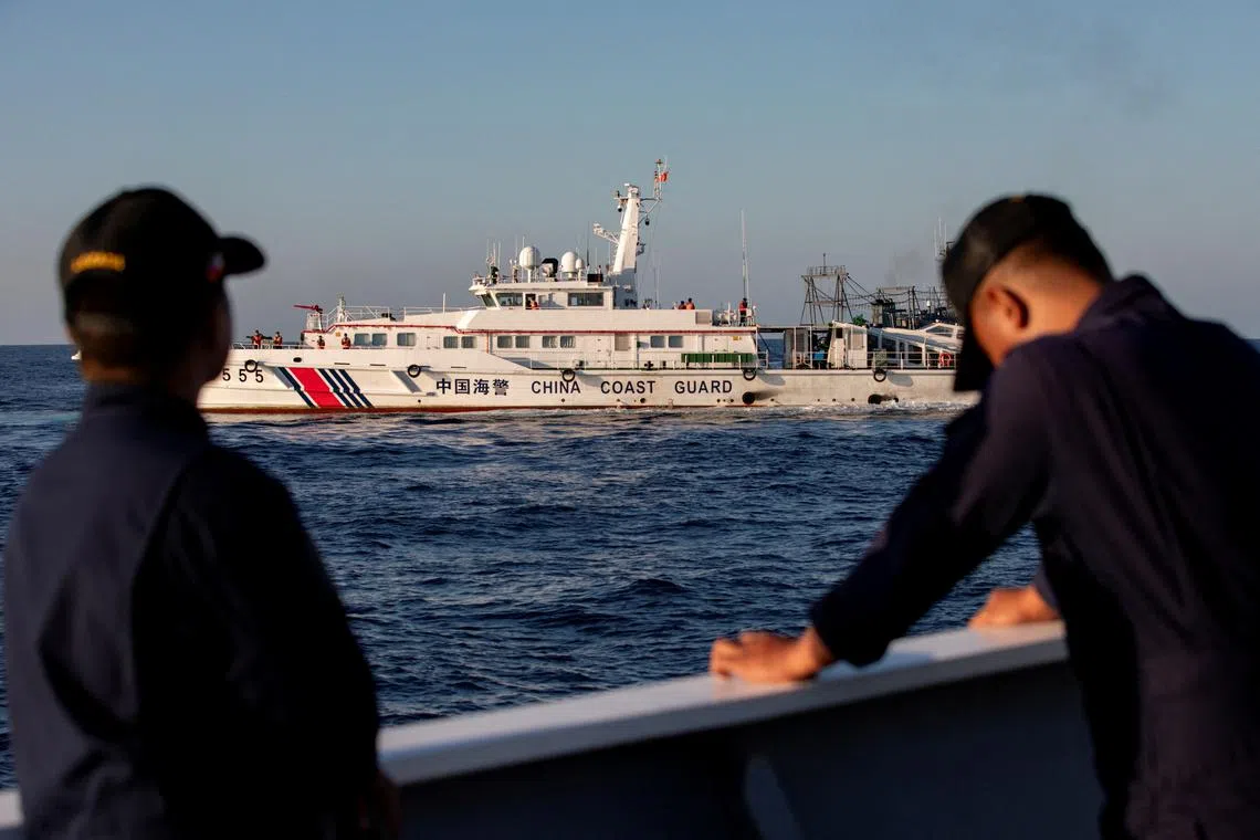 In a photo taken on March 5, 2024, members of the Philippine Coast Guard stand alert as a Chinese Coast Guard vessel blocks their way to a resupply mission at Second Thomas Shoal in the South China Sea.