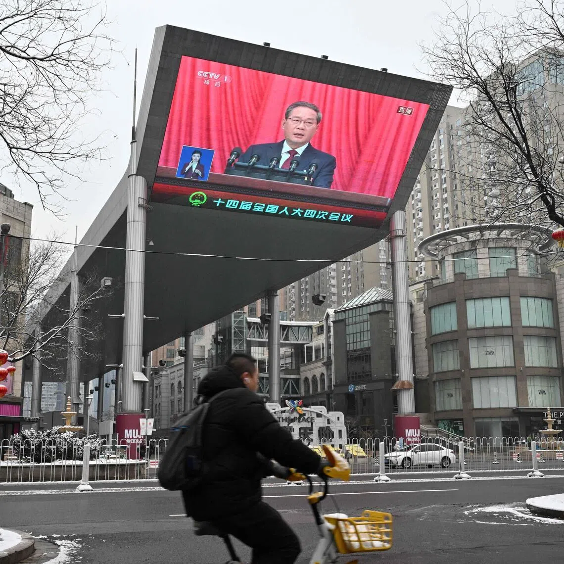 A screen shows Chinese Premier Li Qiang delivering a work report during the opening session of the National People’s Congress (NPC) at the Great Hall of the People, in Beijing on March 5, 2026. (Photo by ADEK BERRY / AFP)
