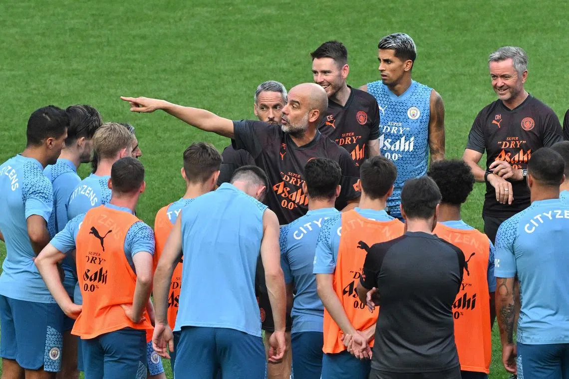 Manchester City's head coach Pep Guardiola (C) speaks with the players during a training session at the Seoul World Cup Stadium in Seoul on July 29, 2023, on the eve of their friendly football match against Atletico Madrid. (Photo by Jung Yeon-je / AFP)