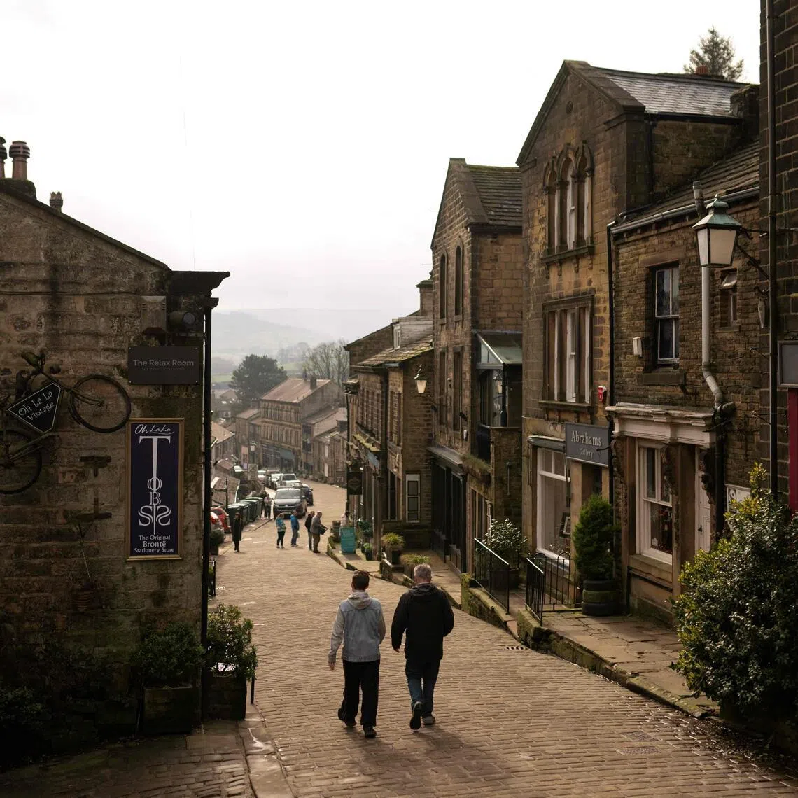 Members of the public walk along Main Street in the village centre of Haworth, northern England, where Emil Bronte and her sisters used to live.