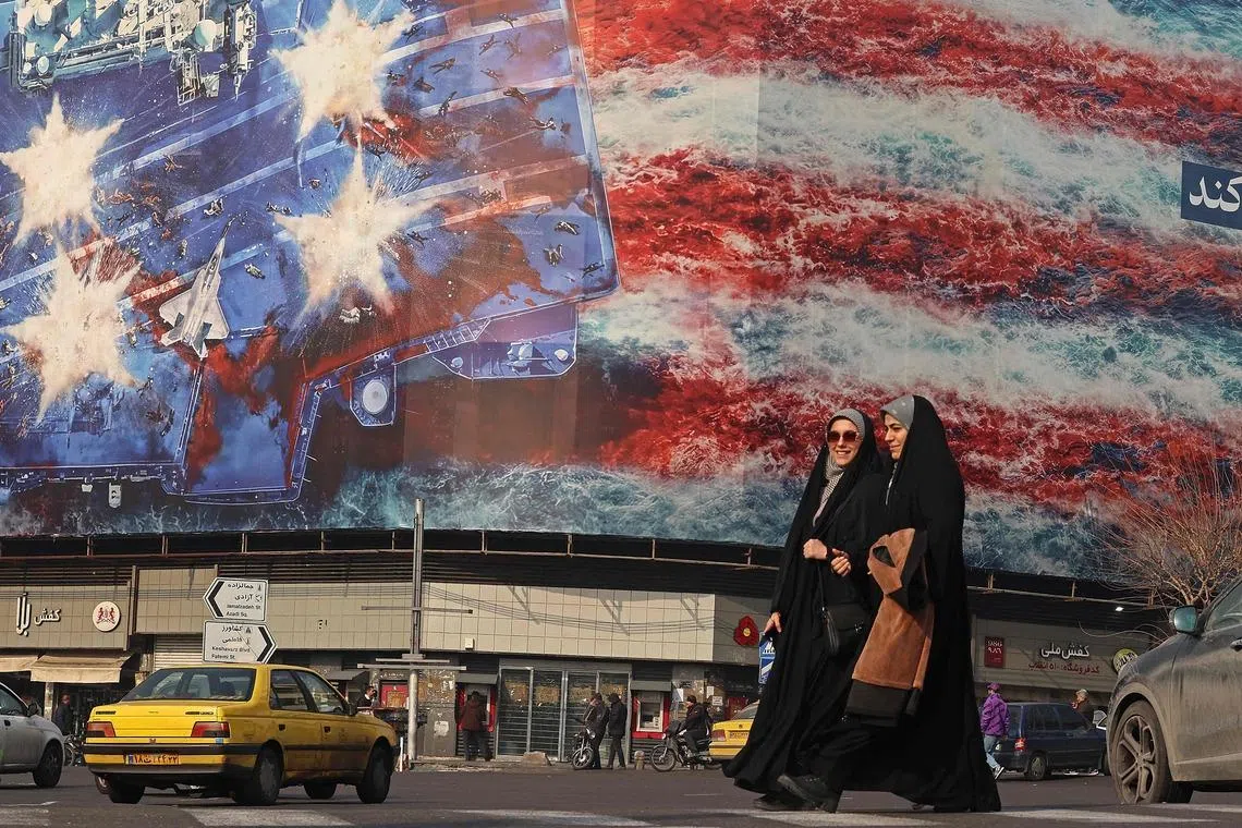 ranian women walking past an anti-US billboard installed on a building at the Enqelab Square in Tehran, Iran on Jan 26, 2026. 