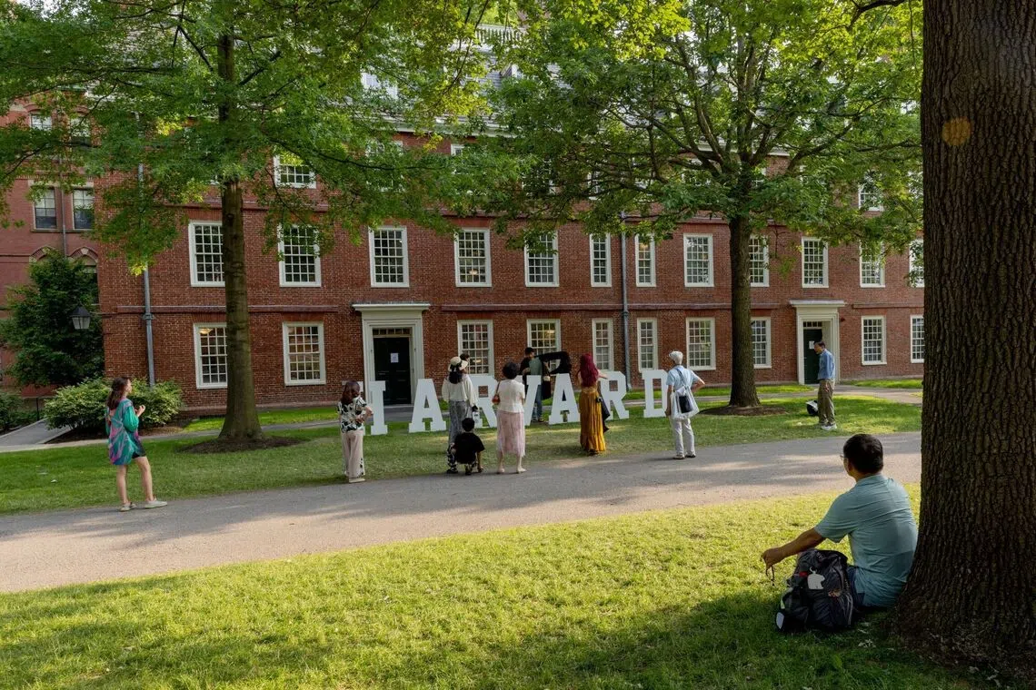 People walking in front of a large red brick building labeled Harvard.