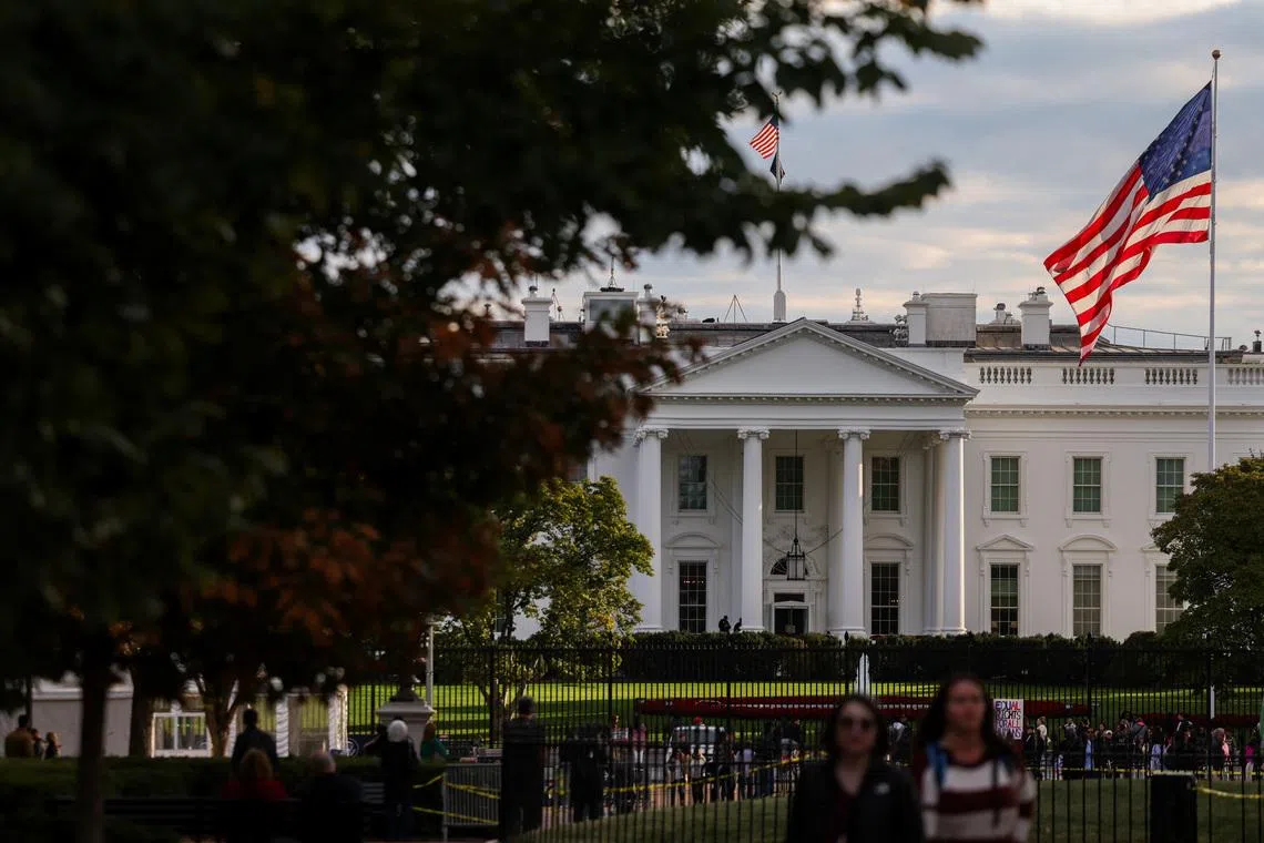 A U.S. flag flies in front of the White House as people walk by, weeks into the continuing U.S. government shutdown, in Washington, D.C., U.S., October 24, 2025. REUTERS/Kylie Cooper
