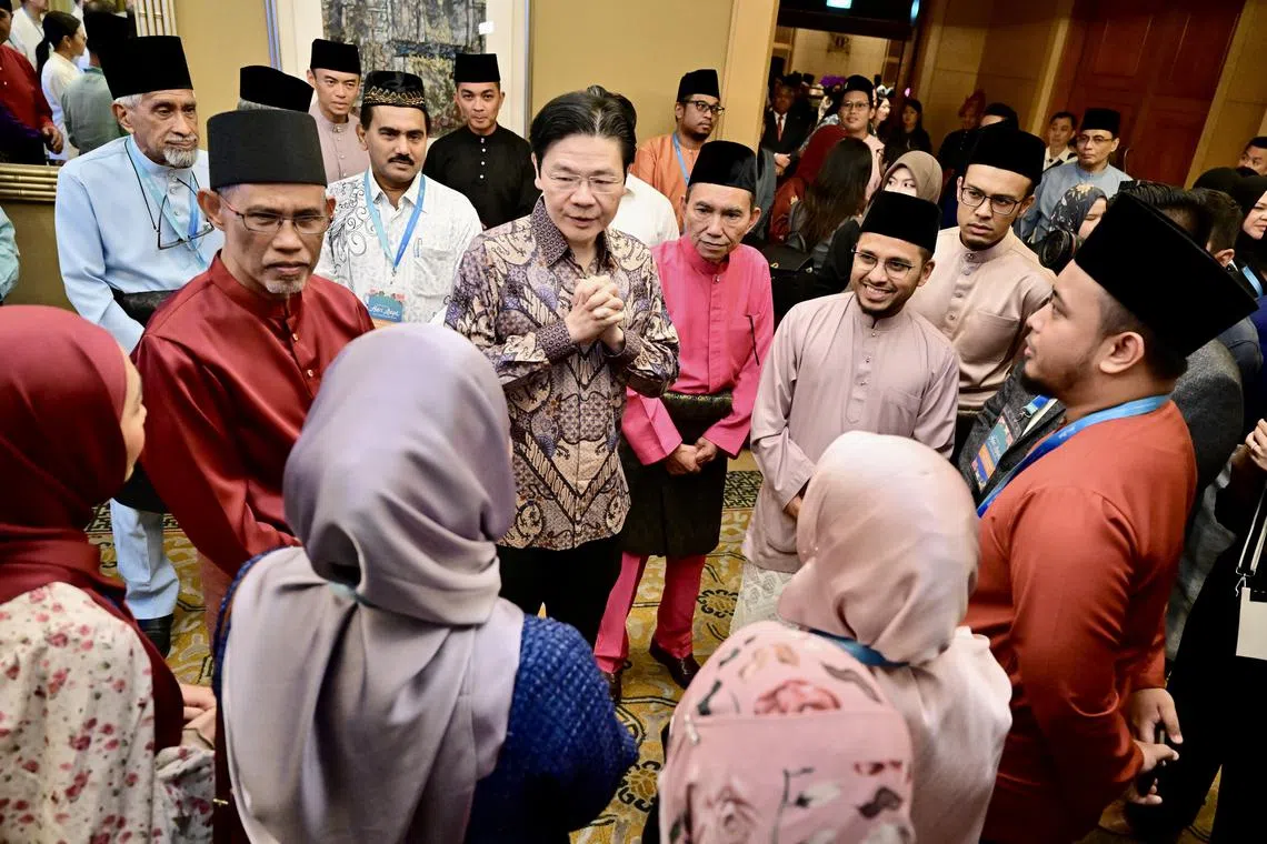 Minister-in-charge of Muslim Affairs Masagos Zulkifli (left) and DPM Lawrence Wong speaking to other guests at the annual Minister’s Hari Raya Get-Together on April 19.