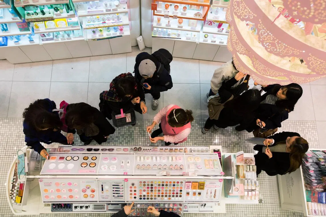 An employee, center, assists customers as they browse cosmetics at an Amorepacific Corp. Etude House store in the Myeongdong shopping district in Seoul, South Korea, on Monday, Feb. 16, 2015. AmorePacific Corp., South Koreas largest cosmetics maker, joins companies such as Hotel Shilla Co. and casino operator Paradise Co. in benefiting from the rising popularity of Korean entertainment and culture, especially in China. Photographer: SeongJoon Cho/Bloomberg