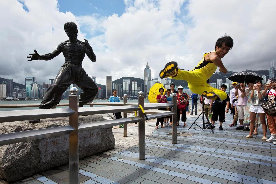 Chinese actor Mei Zhiyong performs a flying kick in front of a bronze statue of gongfu legend Bruce Lee in Hong Kong on Thursday.