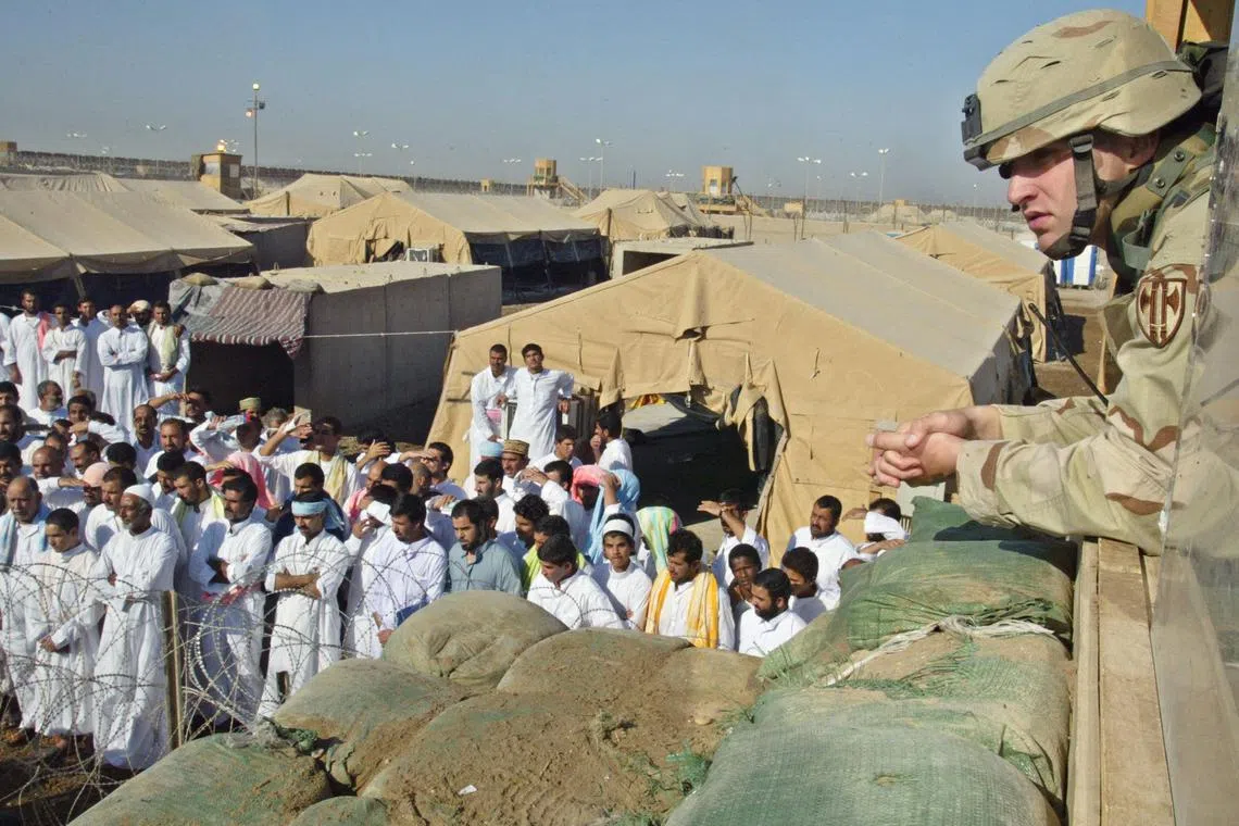 In this 2005 photo, a US soldier watches as detainees are released from Abu Ghraib prison, 25km west of Baghdad.  