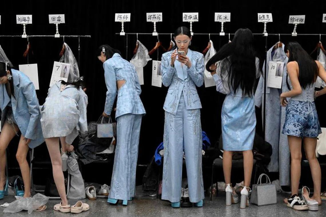 Models prepare backstage before going on the cat walk to showcase a collection by designr Bian Huizhong during the China Fashion Week in Beijing on March 30, 2023.