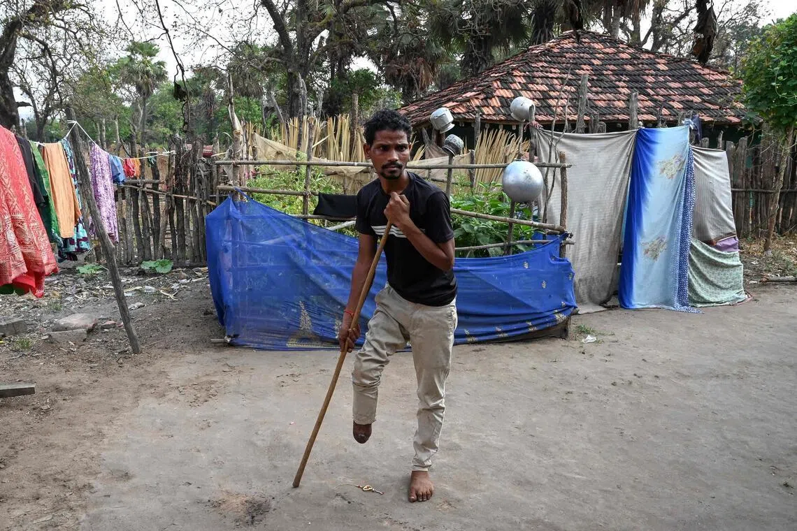 Mr Raju Modiyam, a tribal resident who lost a leg in a landmine explosion, walks with the help of a stick at his residence in the Lankapalli village of Chhattisgarh's Bijapur district on April 1. 