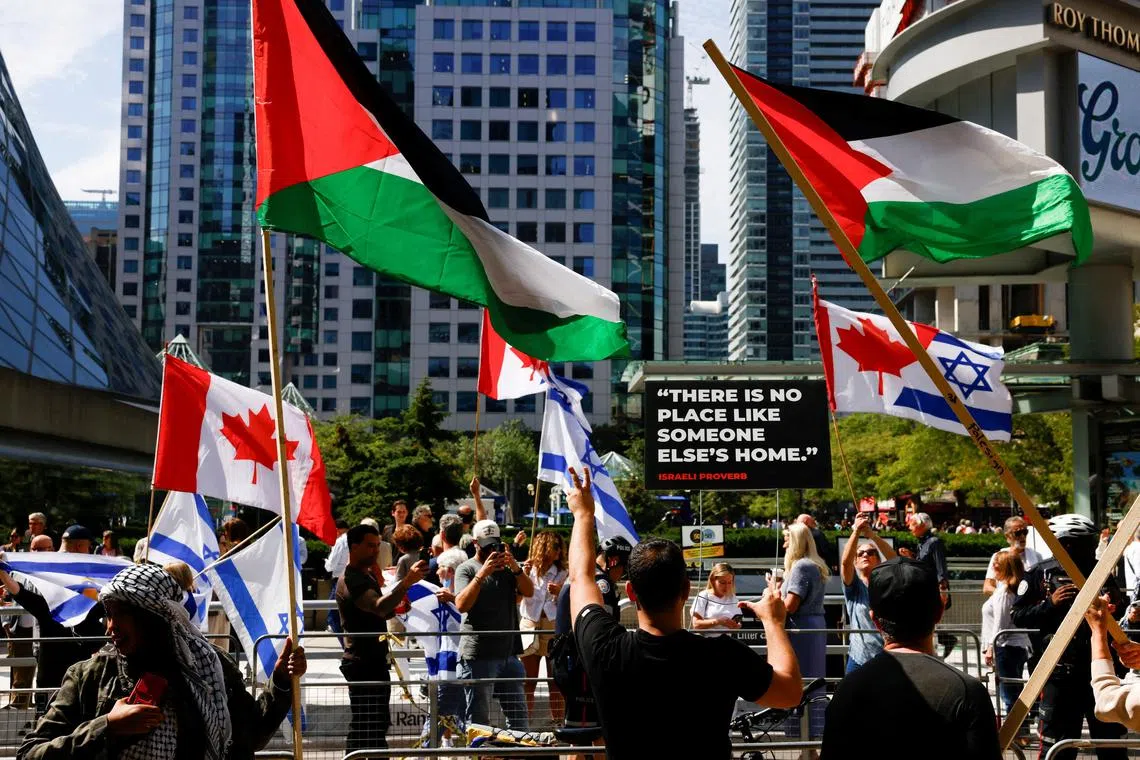 Protesters and counter protesters hold flags during a protest outside the screening of the documentary \"The Road Between Us: The Ultimate Rescue\" about the surprise attack by Hamas on Israel, at the Toronto International Film Festival (TIFF) in Toronto, Ontario, Canada September 10, 2025.  REUTERS/Carlos Osorio