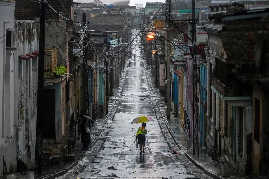 A woman walking in a street before Hurricane Melissa hits the city of Santiago de Cuba, Cuba on Oct 28, 2025. 