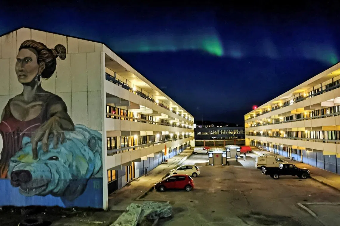 FILE PHOTO: The Aurora Borealis (Northern Lights) is seen behind a building with social housings with a mural in Nuuk, Greenland, September 17, 2021. REUTERS/Hannibal Hanschke/File Photo