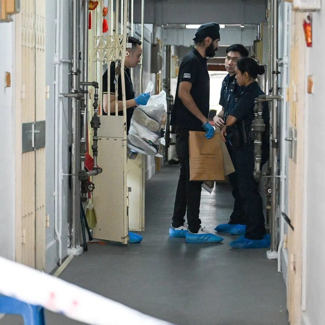 Police officers taking evidence from a flat on the 19th floor of Block 51 Chin Swee Road.