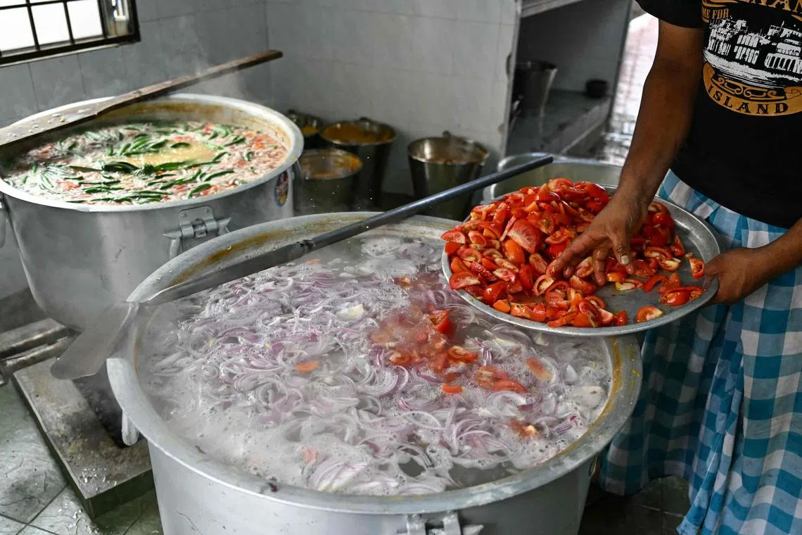 A man pouring tomatoes as he prepares the popular dish 'Bubur Lambuk' at Masjid India during the Muslim holy fasting month of Ramadan in Kuala Lumpur. 