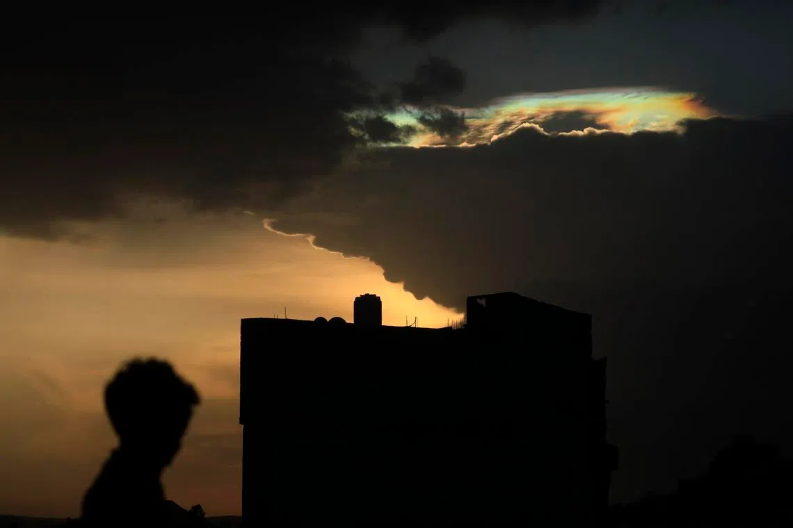 epa12937125 A person is silhouetted as cloud iridescence appears in the sky at sunset, in Sana’a, Yemen, 06 May 2026. Cloud iridescence, also known as irisation, is a colorful optical phenomenon that occurs when sunlight is diffracted by a dense layer of thin clouds, creating rainbow-like hues in the sky. EPA/YAHYA ARHAB