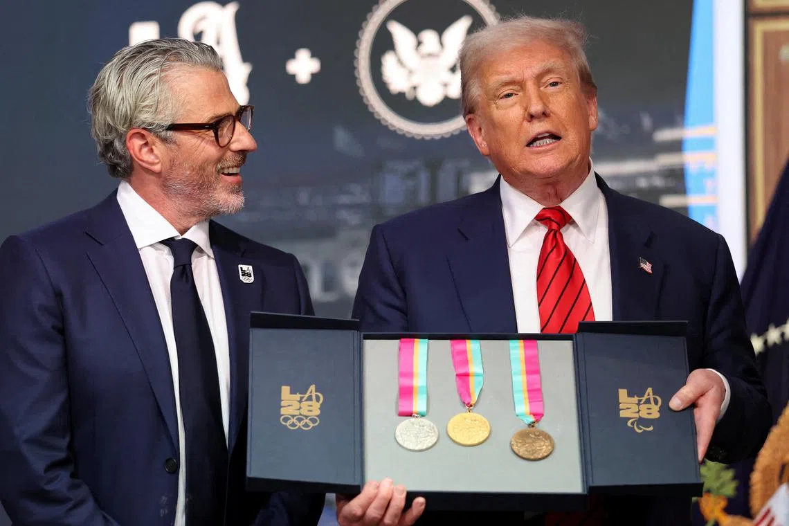 FILE PHOTO: U.S. President Donald Trump, accompanied by LA28 Chairman Casey Wasserman, holds 1984 Los Angeles Olympics medals as he delivers remarks before signing an executive order to create a White House Olympics task force to handle security and other issues related to the LA 2028 Summer Olympics, in the South Court Auditorium on the White House campus in Washington, D.C., U.S., August 5, 2025. REUTERS/Jonathan Ernst/File Photo