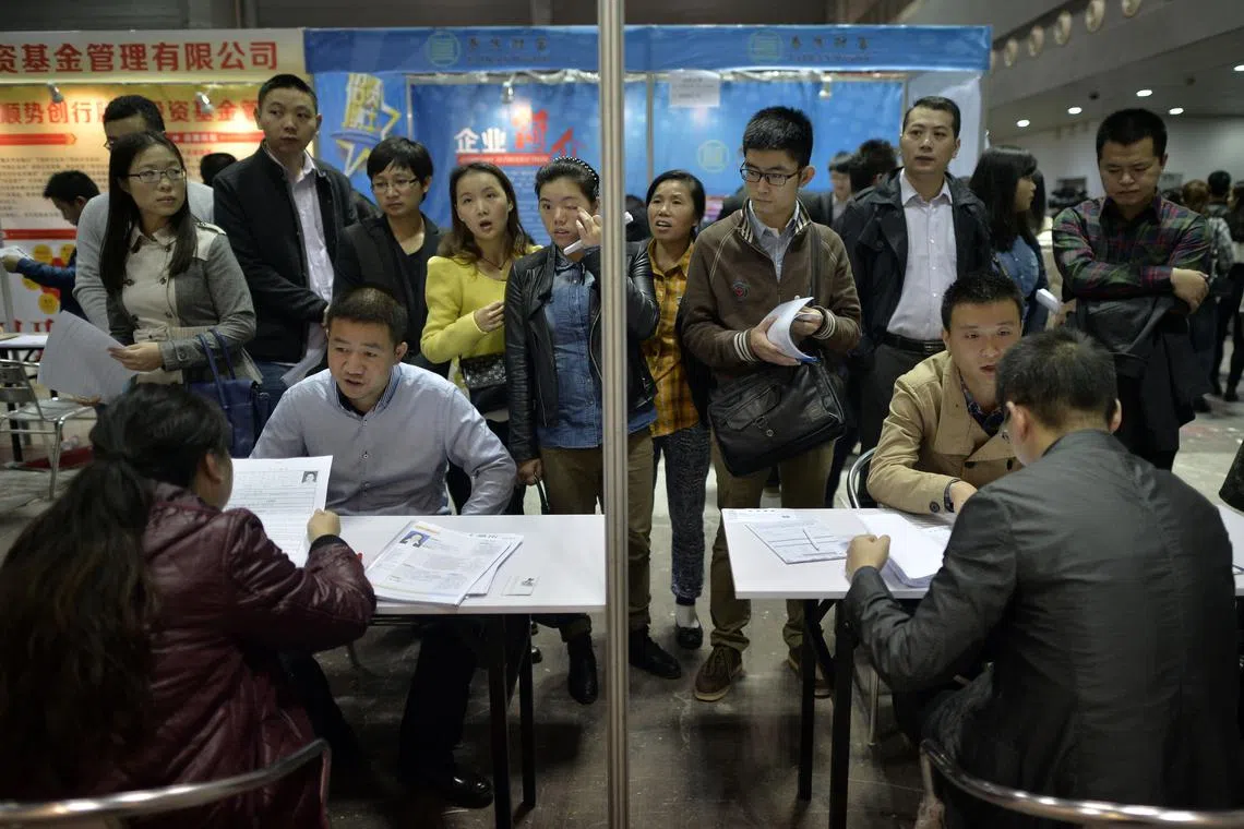 FILE PHOTO: Job seekers (rear) speak to recruiters during their interviews at a job fair in Chongqing municipality, November 2, 2014. REUTERS/Stringer/File Photo