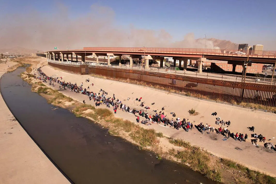Migrants, among them Nicaraguans who were kidnapped by organised crime in the state of Durango and were released days later by the Mexican Army, queue near the border wall after crossing the Rio Bravo river to turn themselves in to U.S. Border Patrol agents to request asylum in the U.S. city of El Paso, Texas, as seen from Ciudad Juarez, Mexico, Dec 12, 2022. 
