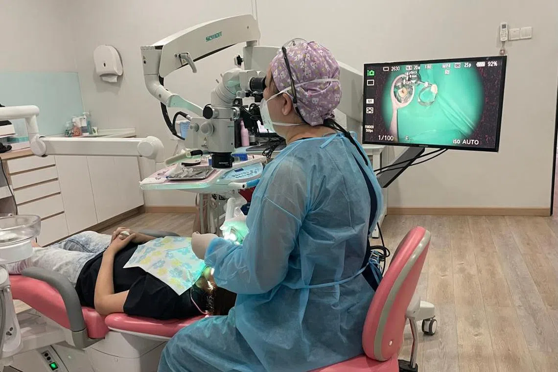 Dr Jolene Lai of Pink and White Dental carrying out a root canal procedure on a patient with the help of a dental microscope and computed imaging.