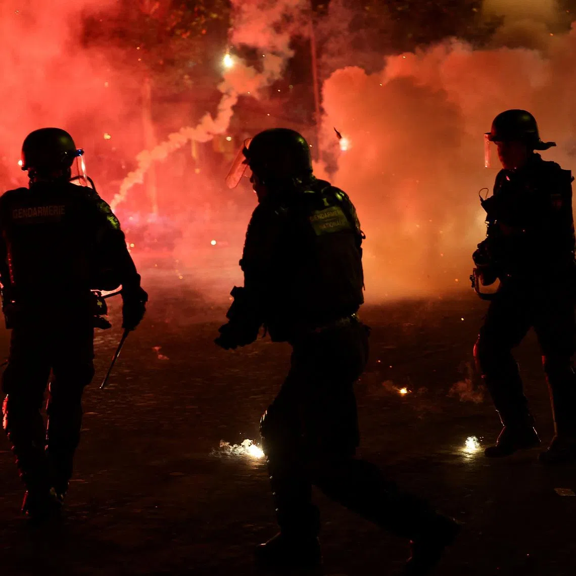 Soccer Football - UEFA Champions League -  Paris St Germain fans celebrate winning the UEFA Champions League - Paris, France - May 31, 2026 Police officers protect themselves from flares after Paris St Germain won the UEFA Champions League REUTERS/Abdul Saboor