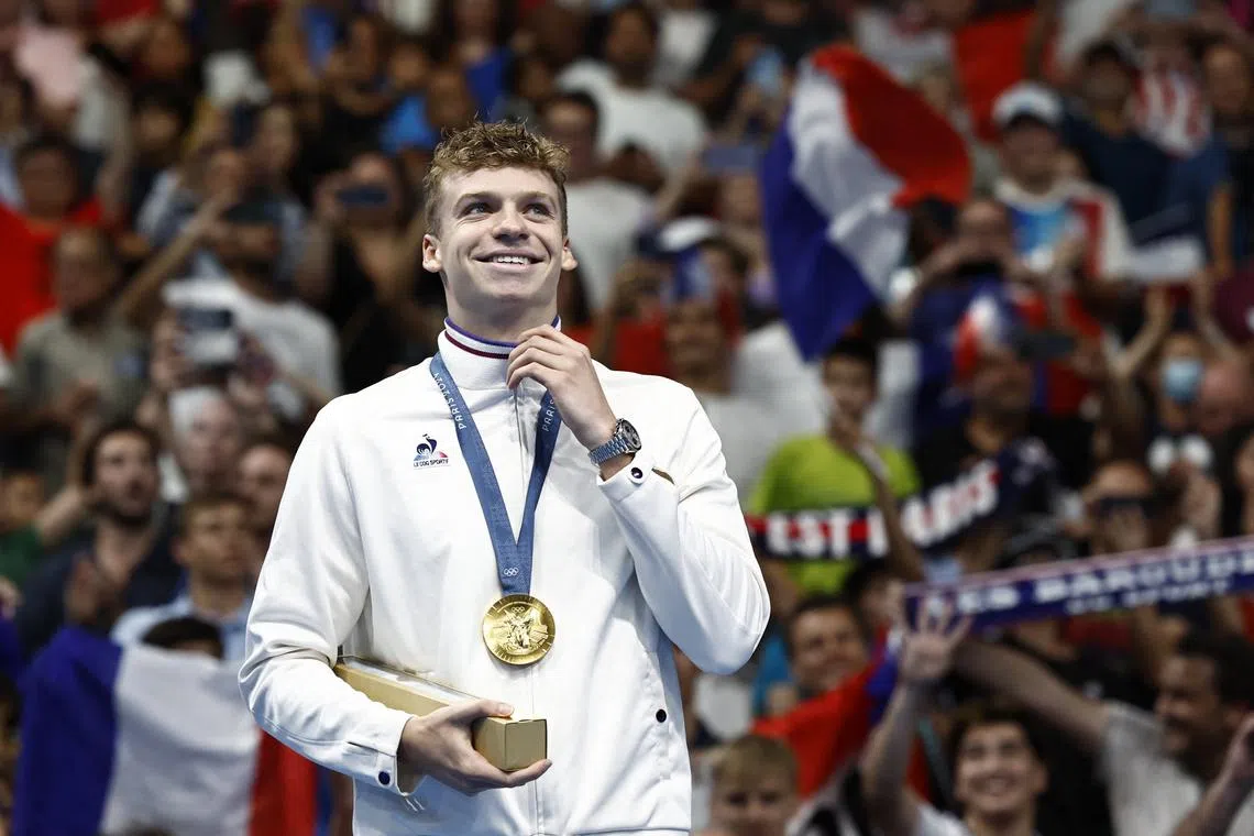 Paris 2024 Olympics - Swimming - Men's 200m Ind. Medley Victory Ceremony - Paris La Defense Arena, Nanterre, France - August 02, 2024. Gold medallist Leon Marchand of France celebrates on the podium after winning gold and setting a new Olympic record. REUTERS/Clodagh Kilcoyne