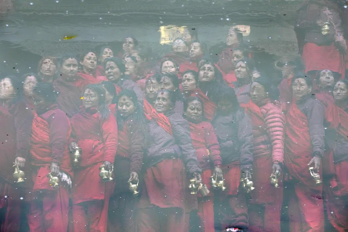 Nepalese Hindu women waiting to collect holy water during the 'Madhav Narayan' festival at the Bagmati River in Kathmandu, Nepal on Feb 9, 2024. The Madhav Narayan festival is a full month-long event devoted to religious fasting, holy bathing and the study of the Swasthani book, which is dedicated to the God Shiva and Goddess Swastania.