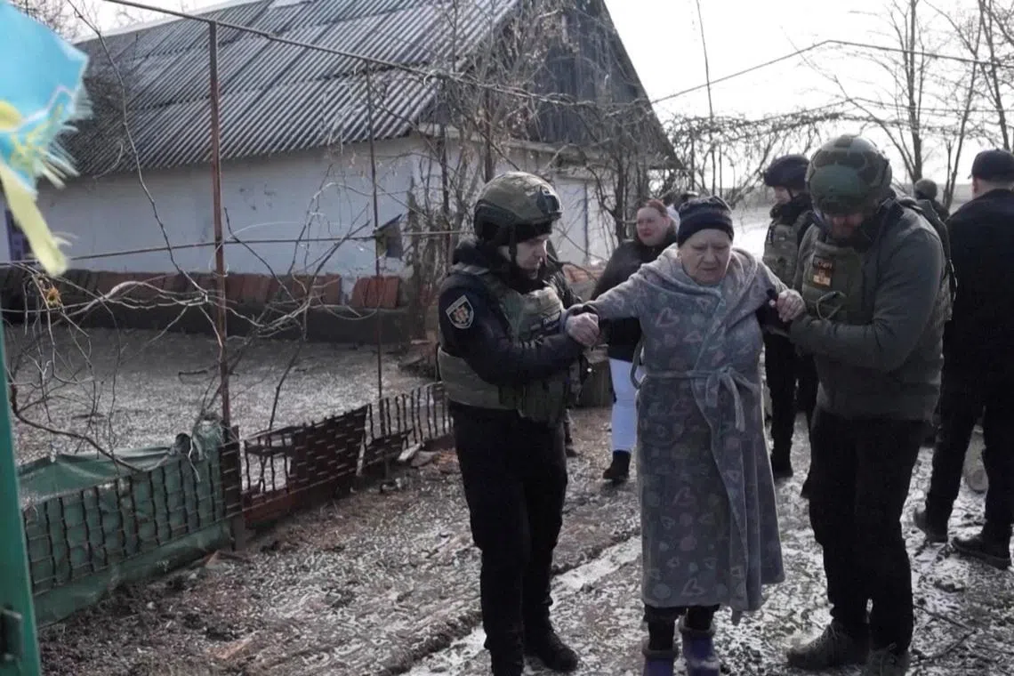 Ukrainian national police officers assist a woman during an evacuation of residents from the Tavriiske and Yurkivka villages in Ukraine's Zaporizhzhia region, amid Russia's attack on Ukraine, in this screengrab from a video, February 3, 2026. Reuters TV via REUTERS