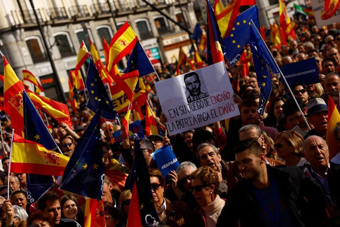 People hold flags as they take part in a protest called for by the Popular Party against a deal reached by Spain's socialists with the Catalan separatist Junts party for government support, which involves amnesties for people involved with Catalonia's failed 2017 independence bid, in Madrid, Spain November 12, 2023. REUTERS/Susana Vera