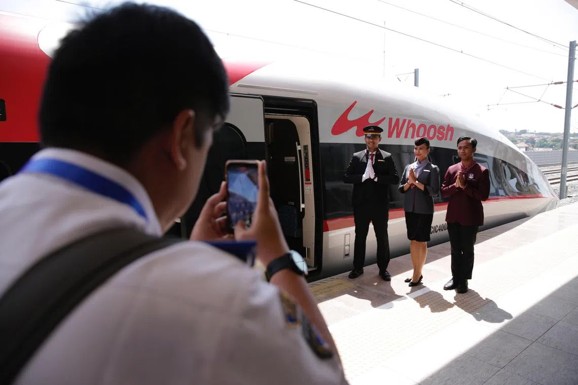 epa10894934 A man takes a picture of rail workers standing next to the Jakarta-Bandung High-Speed Train during an inauguration ceremony, lead by Indonesian President Joko Widodo (not pictured), at Halim Station in Jakarta, Indonesia, 02 October 2023. Joko Widodo inaugurated the Jakarta-Bandung High-Speed Train at Halim Station. The Jakarta-Bandung high-speed train, named Whoosh, is the first in Indonesia and also the first in Southeast Asia. This fast train has a maximum speed of 350 kilometers per hour.  EPA-EFE/ADI WEDA