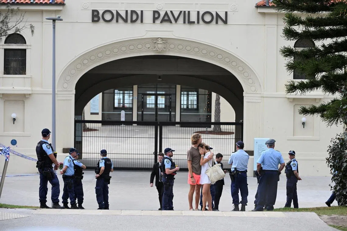 Two people embrace as police officers stand guard outside Bondi Pavilion following the attack on a Jewish holiday celebration at Sydney's Bondi Beach, in Sydney, Australia, December 15, 2025. REUTERS/Flavio Brancaleone/File Photo