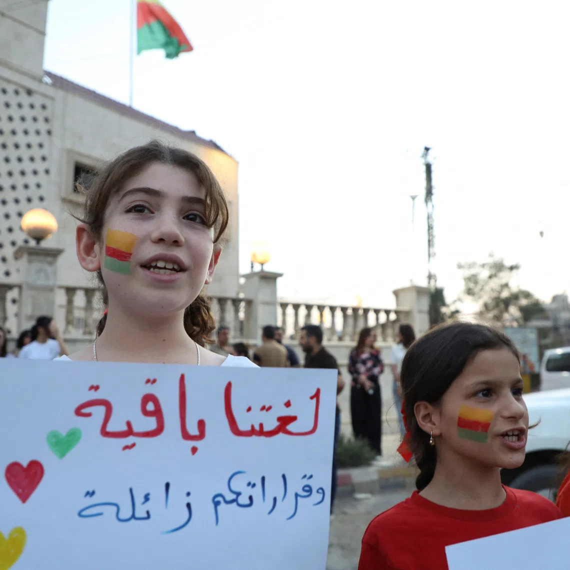 A girl holds a sign reading \"Our language remains, your decisions will fade\" during a gathering in Qamishli, Syria, August 31, 2026. REUTERS/Orhan Qereman