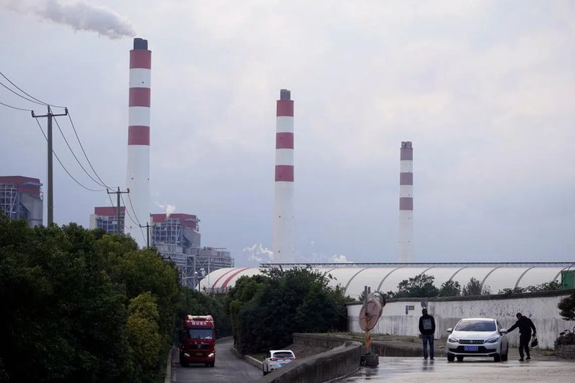 FILE PHOTO: Men stand by a car near a coal-fired power plant in Shanghai, China October 21, 2021. REUTERS/Aly Song/File Photo