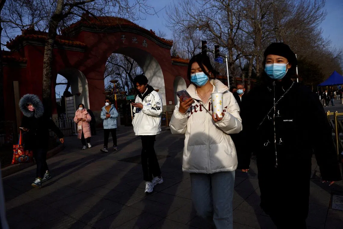 FILE PHOTO: People, wearing masks to prevent coronavirus disease (COVID-19), walk along the street in Beijing, China, February 14, 2023. REUTERS/Tingshu Wang/File Photo