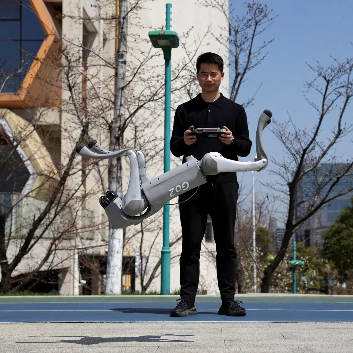 FILE PHOTO: Huang Jiawei, Unitree's marketing director, operates a Go2 robot dog to perform a backflip during a demonstration to Reuters at a park in Hangzhou, Zhejiang province, China March 21, 2025. REUTERS/Florence Lo/File Photo