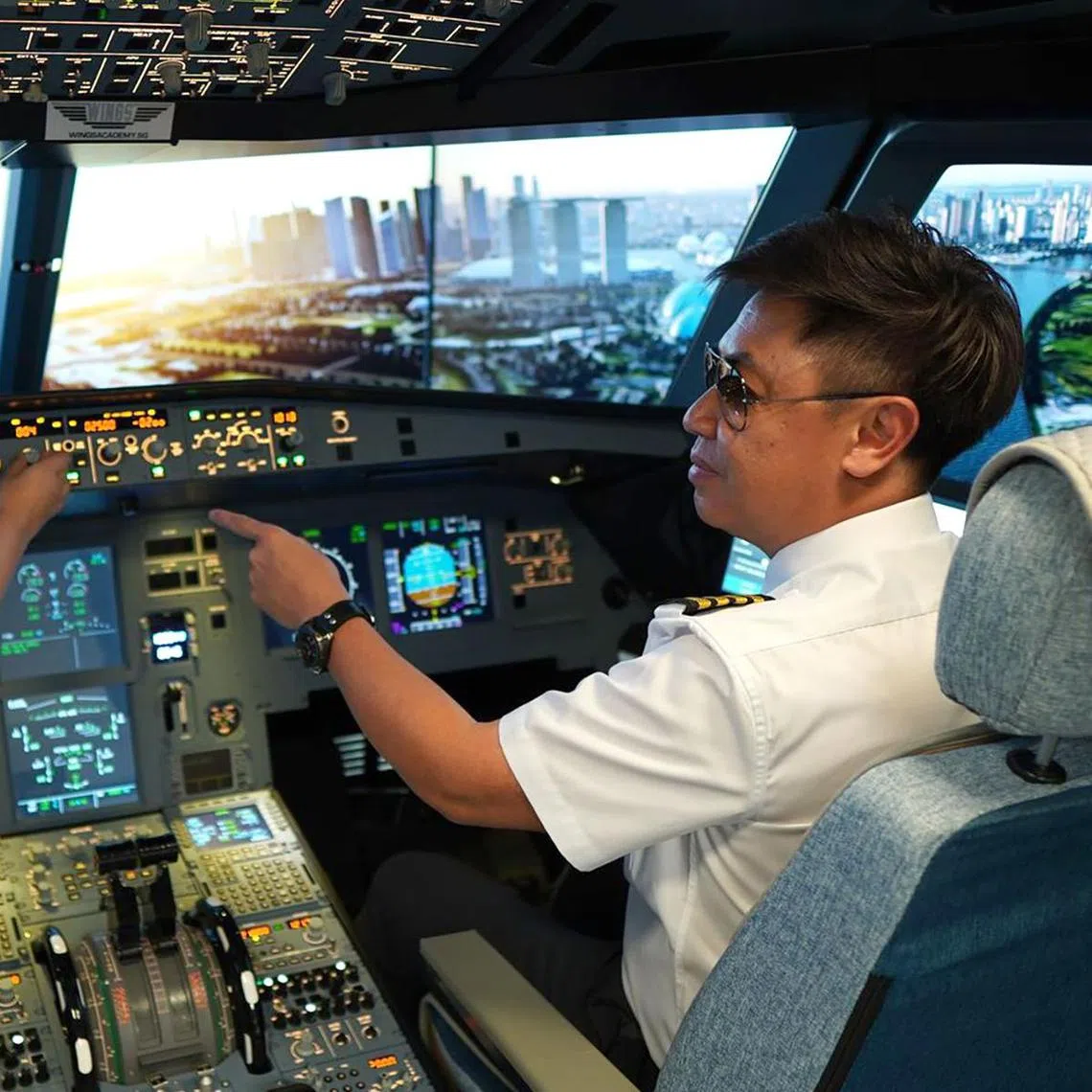 A flying instructor teaching a student in an A320 flight simulator at WingsAcademy.sg.
