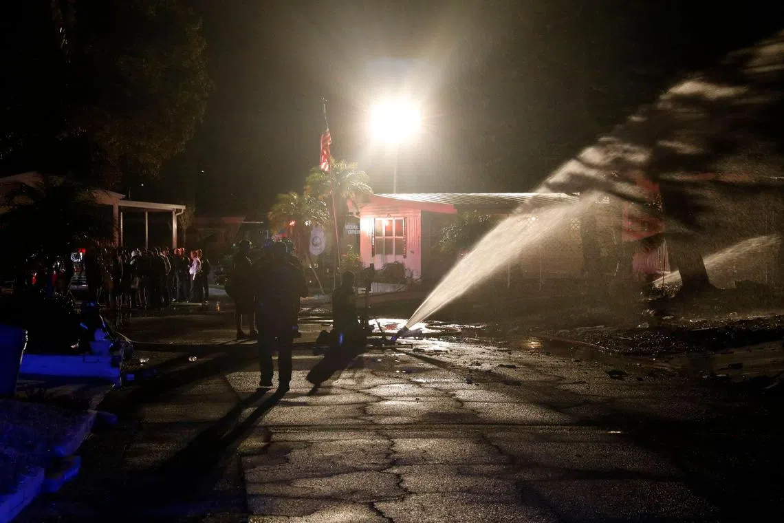 Firefighters work to put out a fire after a small plane crashed into the Bayside Waters mobile home park in Clearwater, Florida.