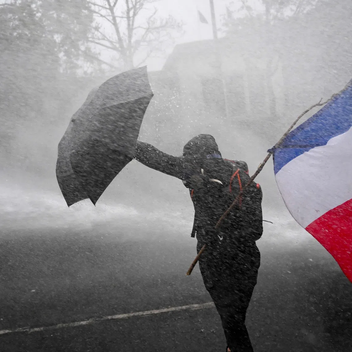A flag-waving French protester holding off police water cannon during protests on Oct 24. Marine Le Pen is likely to come to power next year, propelled by widespread discontent against the centrist government.