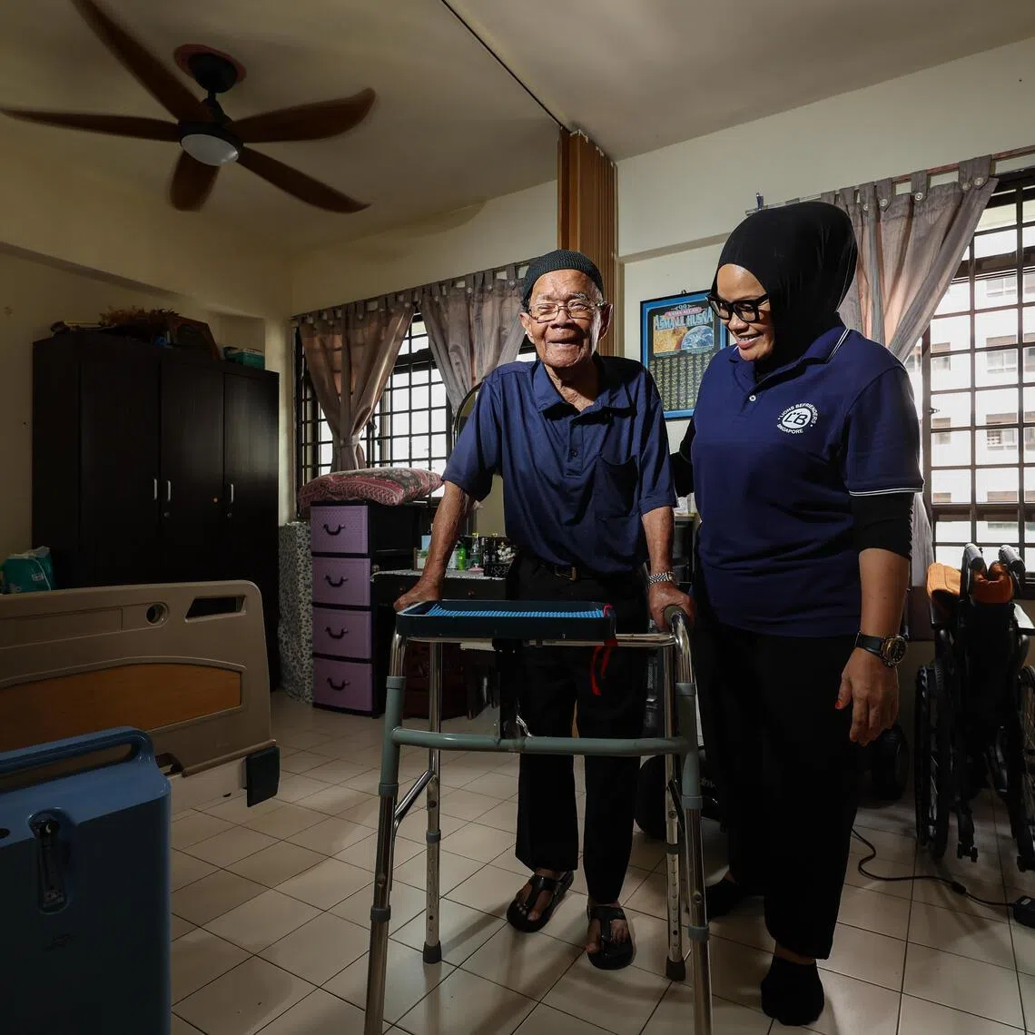 Healthcare assistant Radiana Ahmad (right) tending to an elderly patient at his home in Clementi. Despite working in an AI-resilient sector, she feels pressure to keep up with the technology.