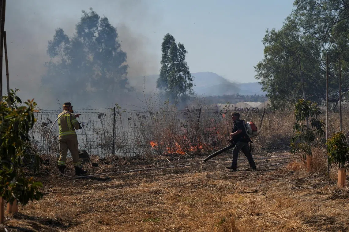 Israeli fire-fighter and another man work to take control over fire following rocket attacks from Lebanon, amid ongoing cross-border hostilities between Hezbollah and Israeli forces, in the Israeli-occupied Golan Heights, June 11, 2024. REUTERS/Ayal Margolin