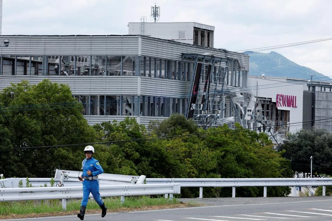 A policeman running past the damaged Aeon Mall shopping centre on July 29.