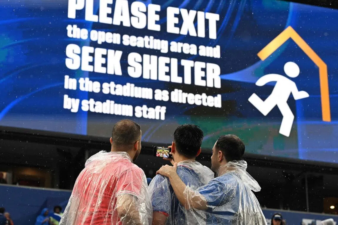 Fans take a selfie in front of a screen showing an evacuation warning during the 2026 World Cup Group I football match between France and Iraq at the Philadelphia Stadium.