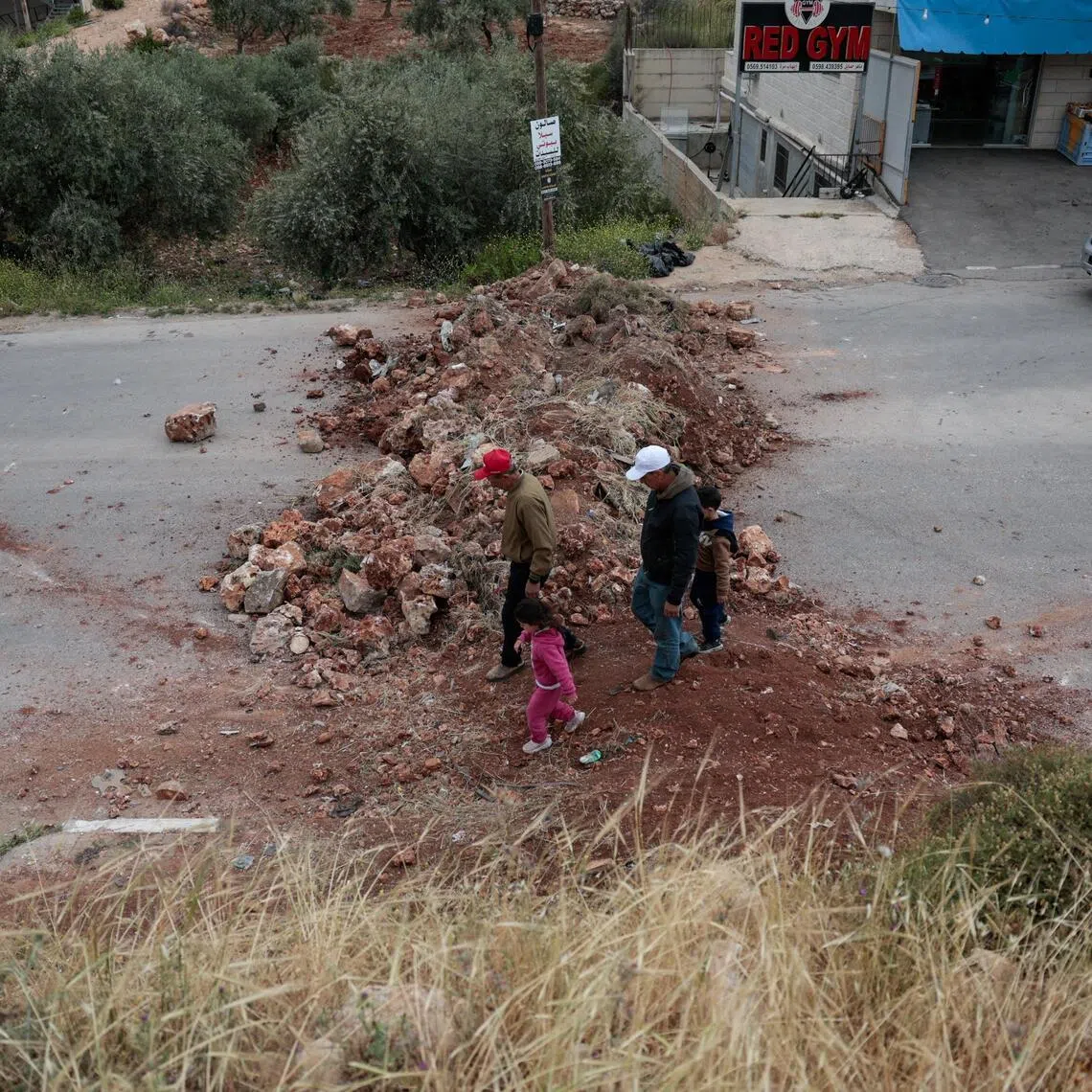 Palestinians walk across a soil barrier, erected by the Israeli army, blocking an entrance to the village of Turmus Aya in the Israeli-occupied West Bank on May 6.